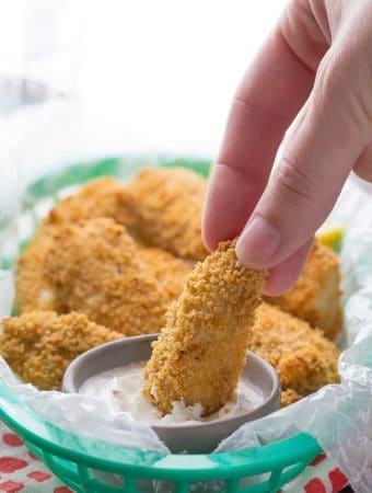 hand dipping a whole wheat chicken strip into sauce