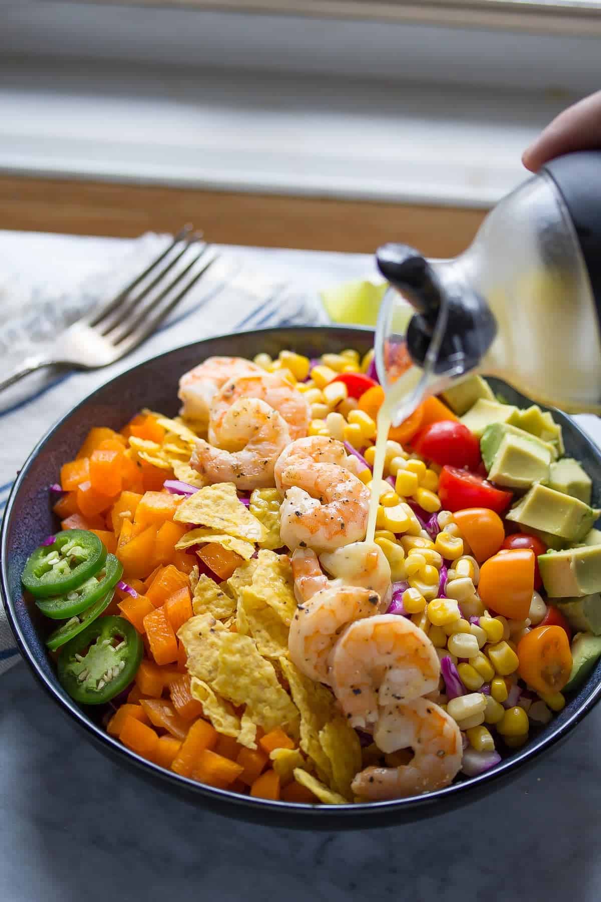 A light and fresh shrimp taco salad recipe that is packed full of veggies and tossed in a honey-lime vinaigrette. Ready in 20 minutes!