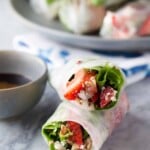 two strawberry spinach salad rolls stacked with dipping sauce