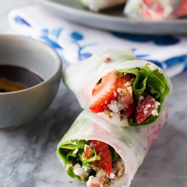 two strawberry spinach salad rolls stacked with dipping sauce