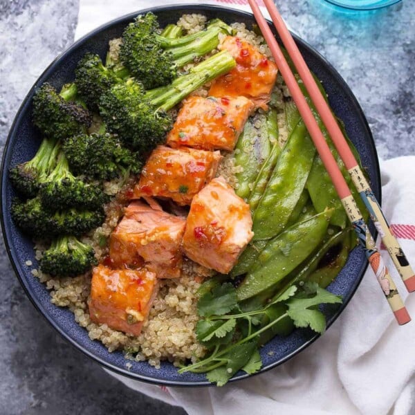 overhead shot of sweet chili salmon broccoli quinoa bowl with chop sticks