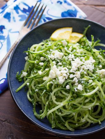 spiralized cucumber feta and mint salad on blue plate with lemon slices