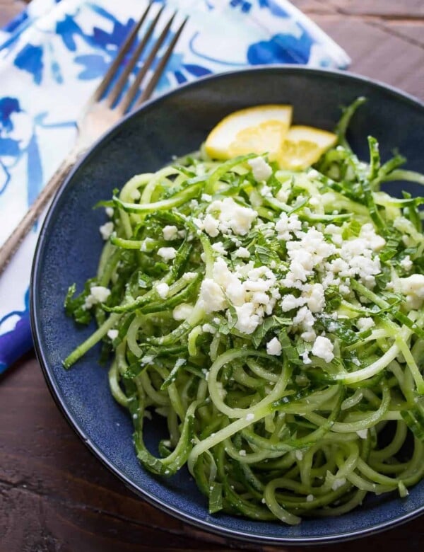 spiralized cucumber feta and mint salad on blue plate with lemon slices