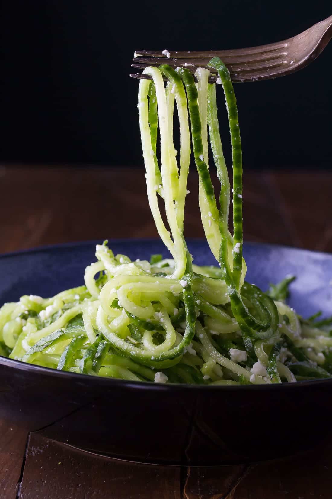 Fork scooping up Cucumber Salad out of blue bowl