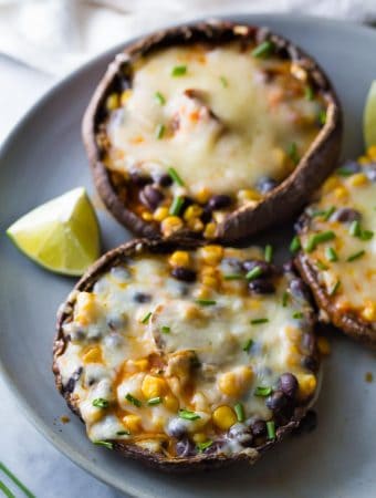 enchilada stuffed grilled portobello mushrooms on gray plate with lime