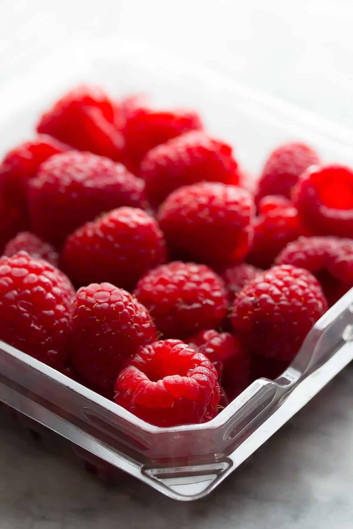 close up view of a pint of raspberries