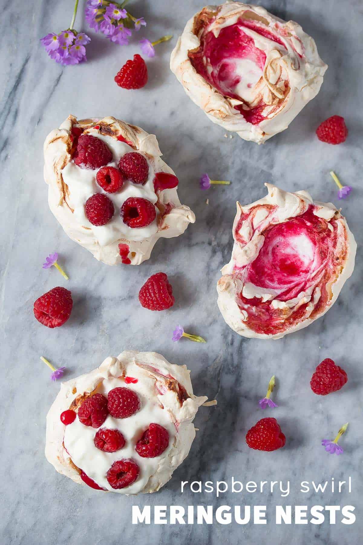 overhead view of 4 raspberry swirled meringue nests; 2 filled with whipped cream and berries