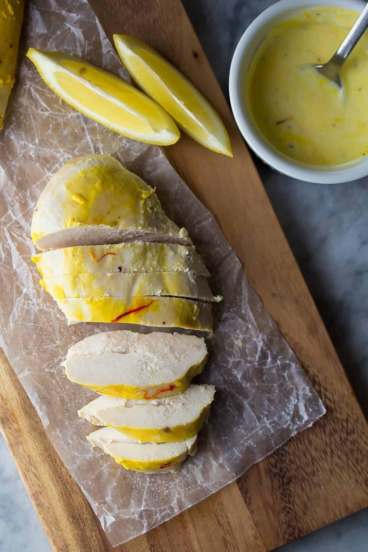overhead view of saffron chicken on cutting board with lemon slices