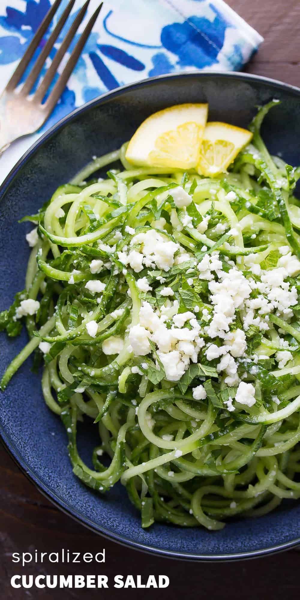 Plated Spiralized Cucumber Salad with Mint & Feta on top and lemon slices on the side