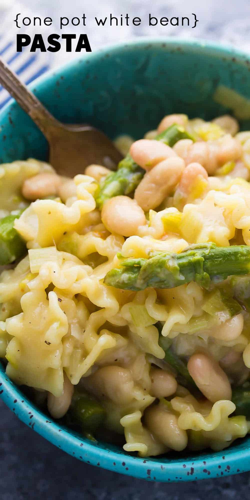 close up shot of One Pot White Bean Pasta in blue bowl with a fork