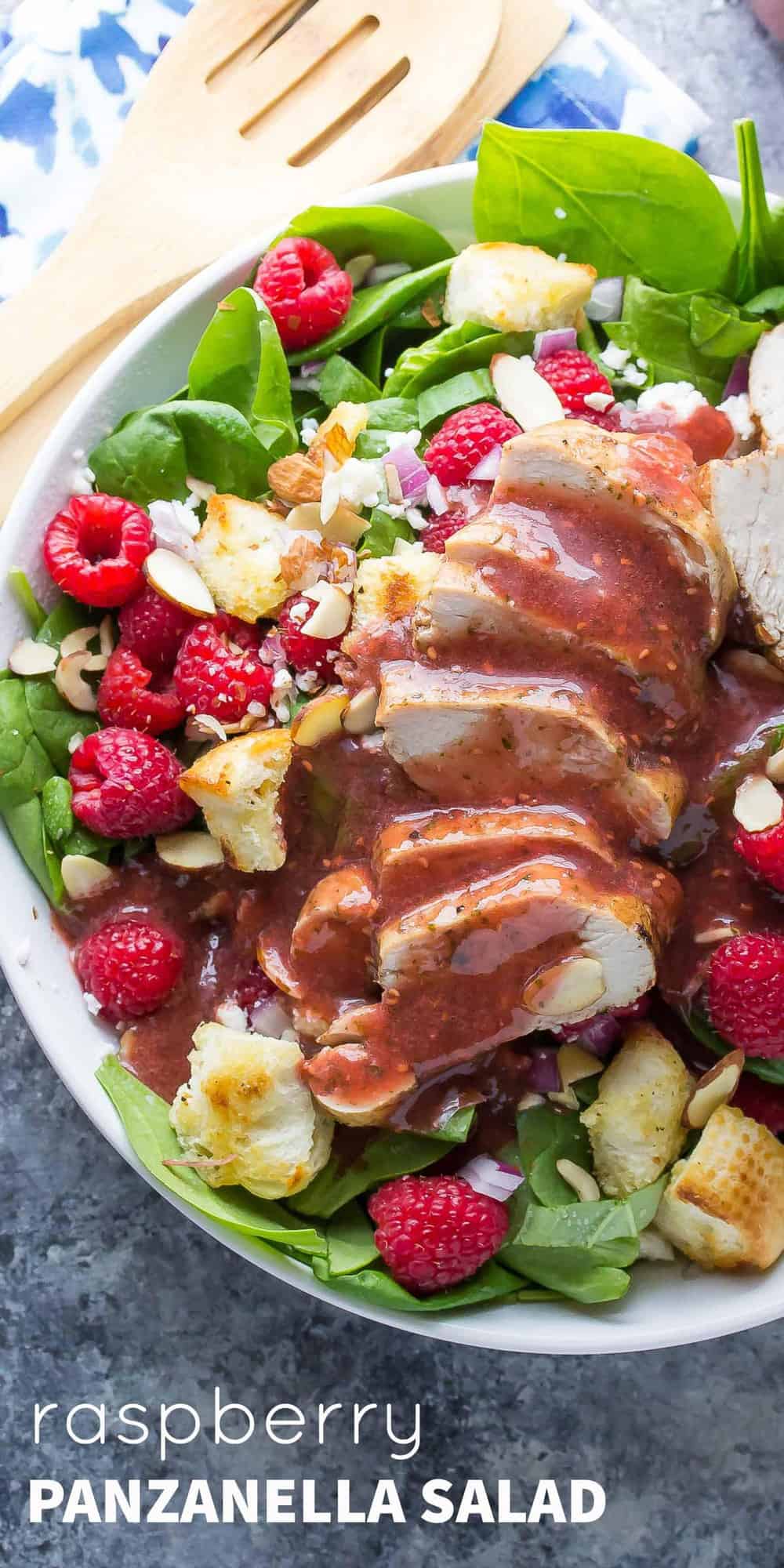 raspberry spinach panzanella salad in a bowl plate, drizzled with raspberry dressing