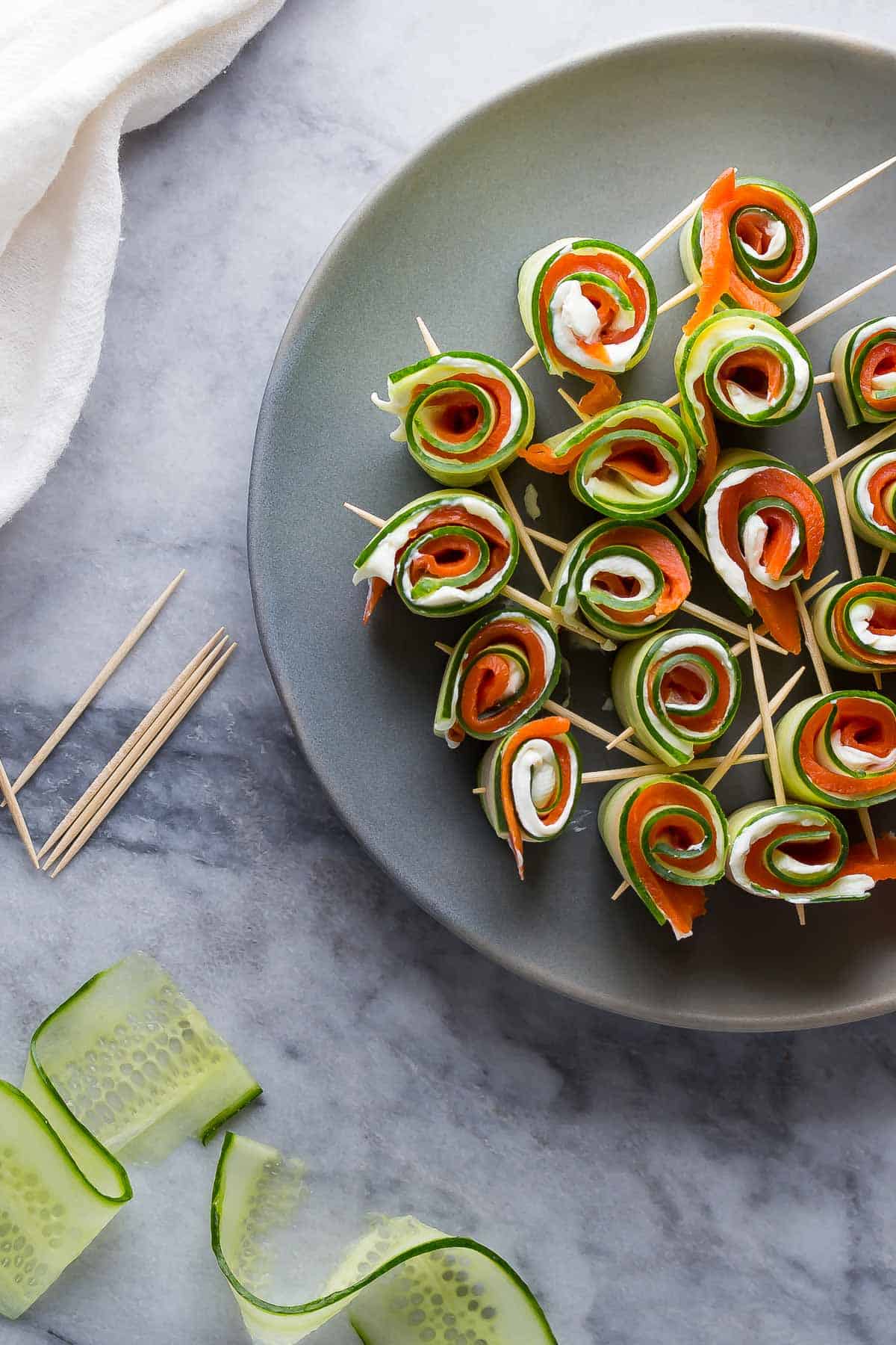 overhead view of Smoked salmon cucumber roll ups plated with toothpicks through them 