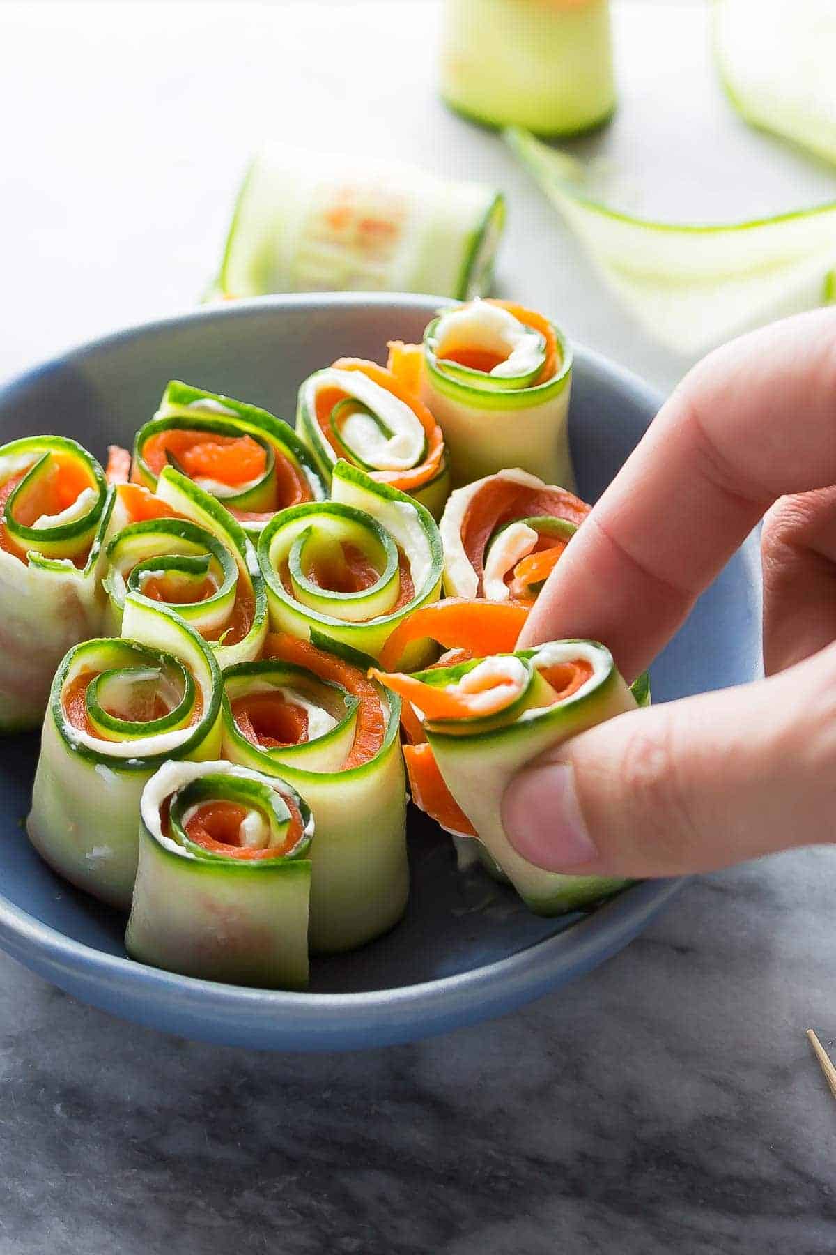 Smoked salmon cucumber roll-ups plated in a blue bowl