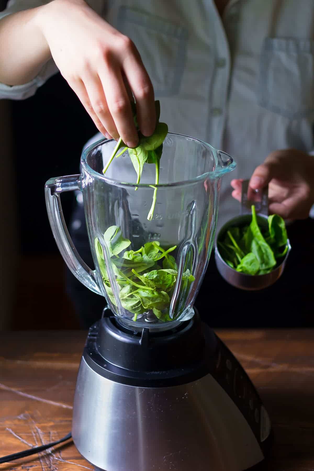 placing spinach into a blender
