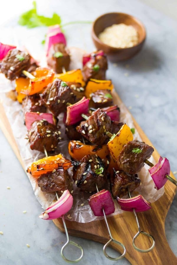 three korean beef skewers on wood cutting board