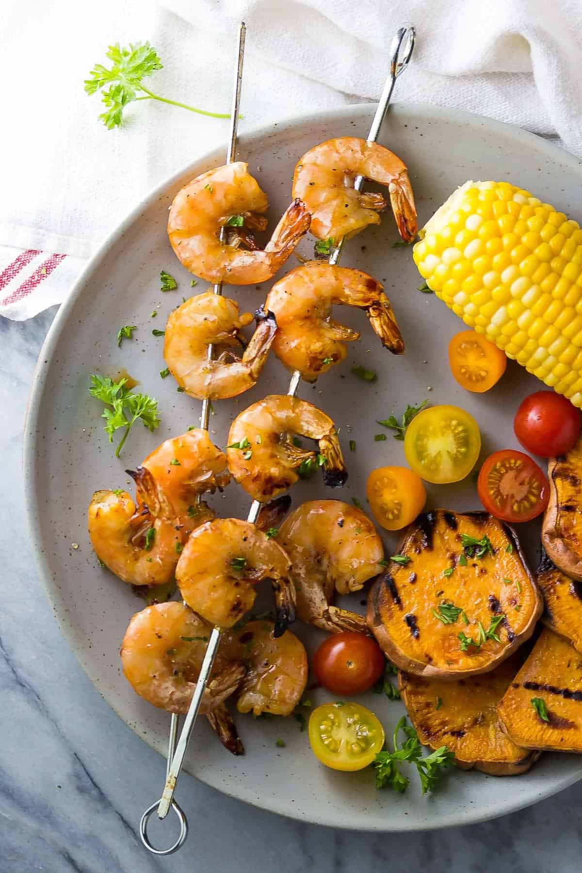 Chipotle Grilled Shrimp Skewers on plate with grilled sweet potatoes, corn and tomatoes