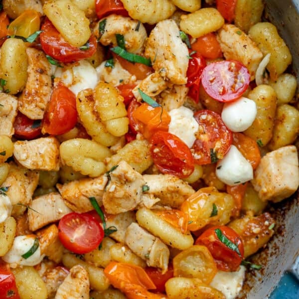 an overhead shot of chicken, gnocchi and tomatoes in a skillet