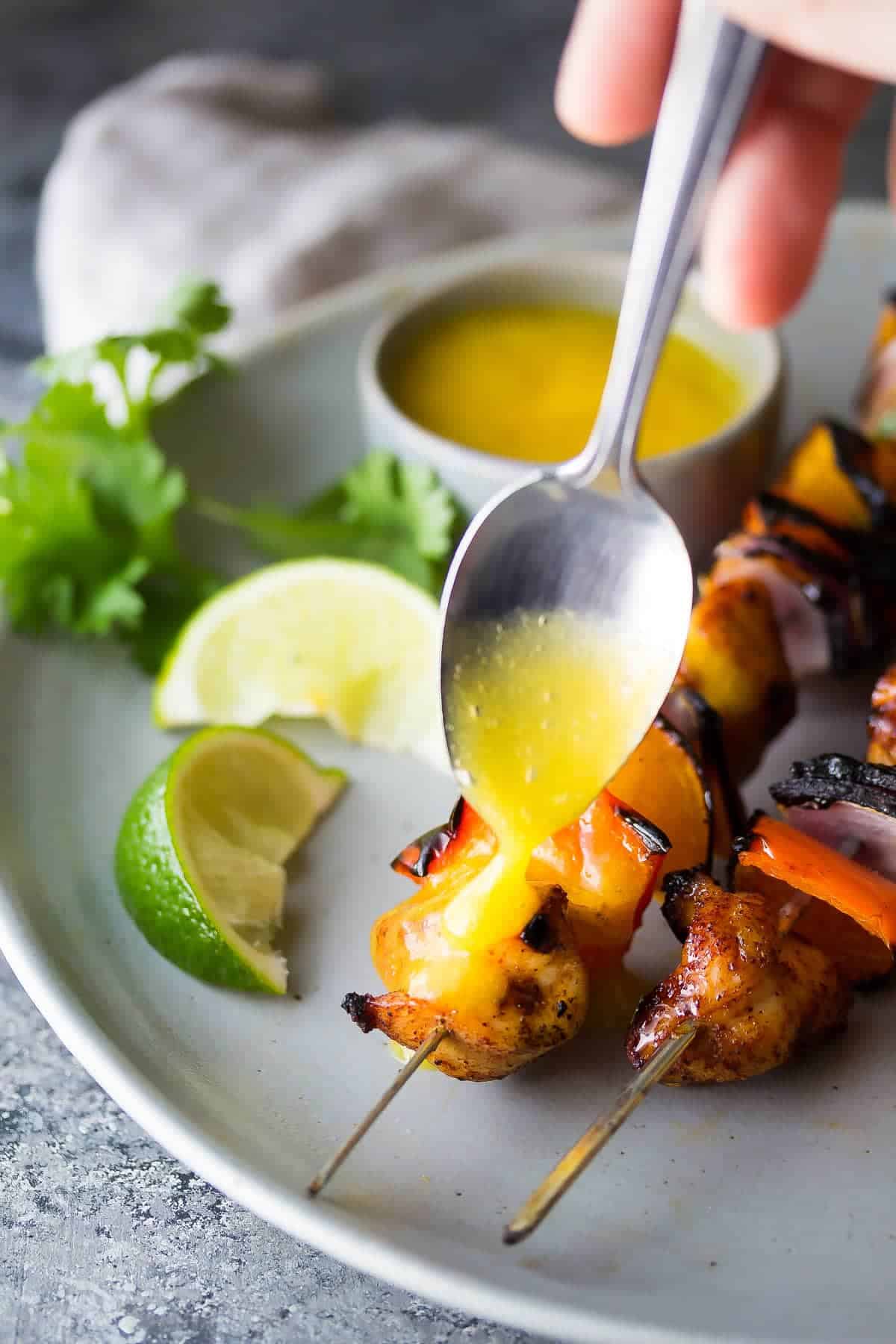 Chili Lime Chicken Skewers with Mango Sauce being drizzled over them