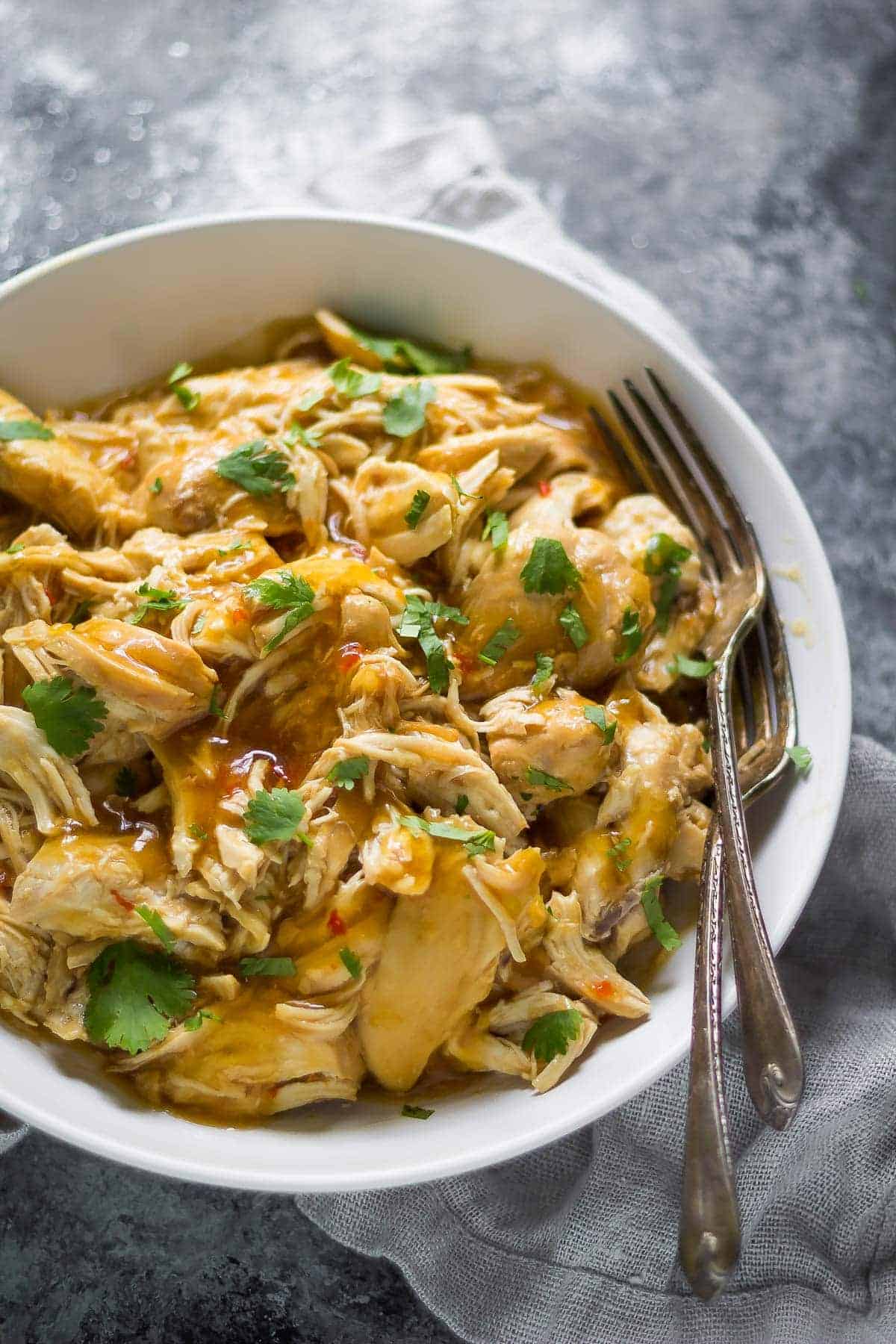 overhead view of a bowl of slow cooker sweet chili chicken with two forks