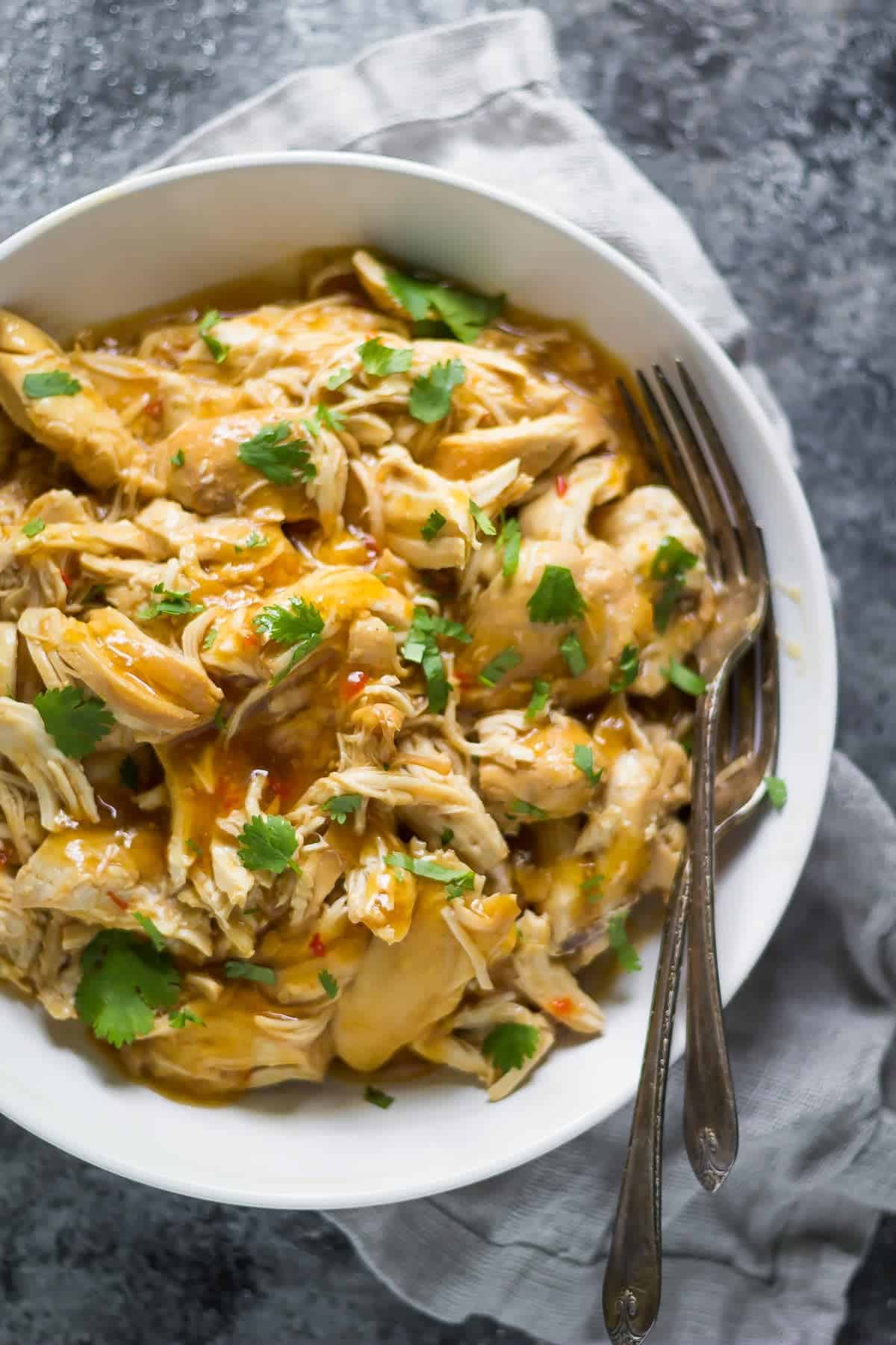 overhead view of a bowl of slow cooker sweet chili chicken with two forks