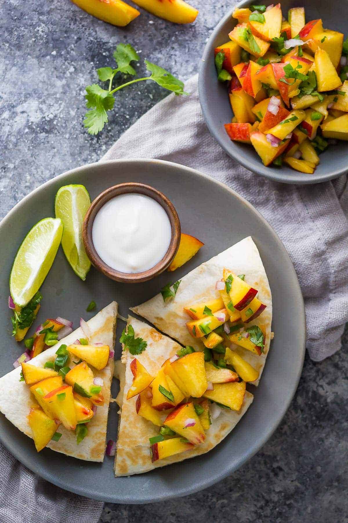 Sweet Chili Chicken Quesadillas with Peach Salsa on a plate with sour cream for dipping