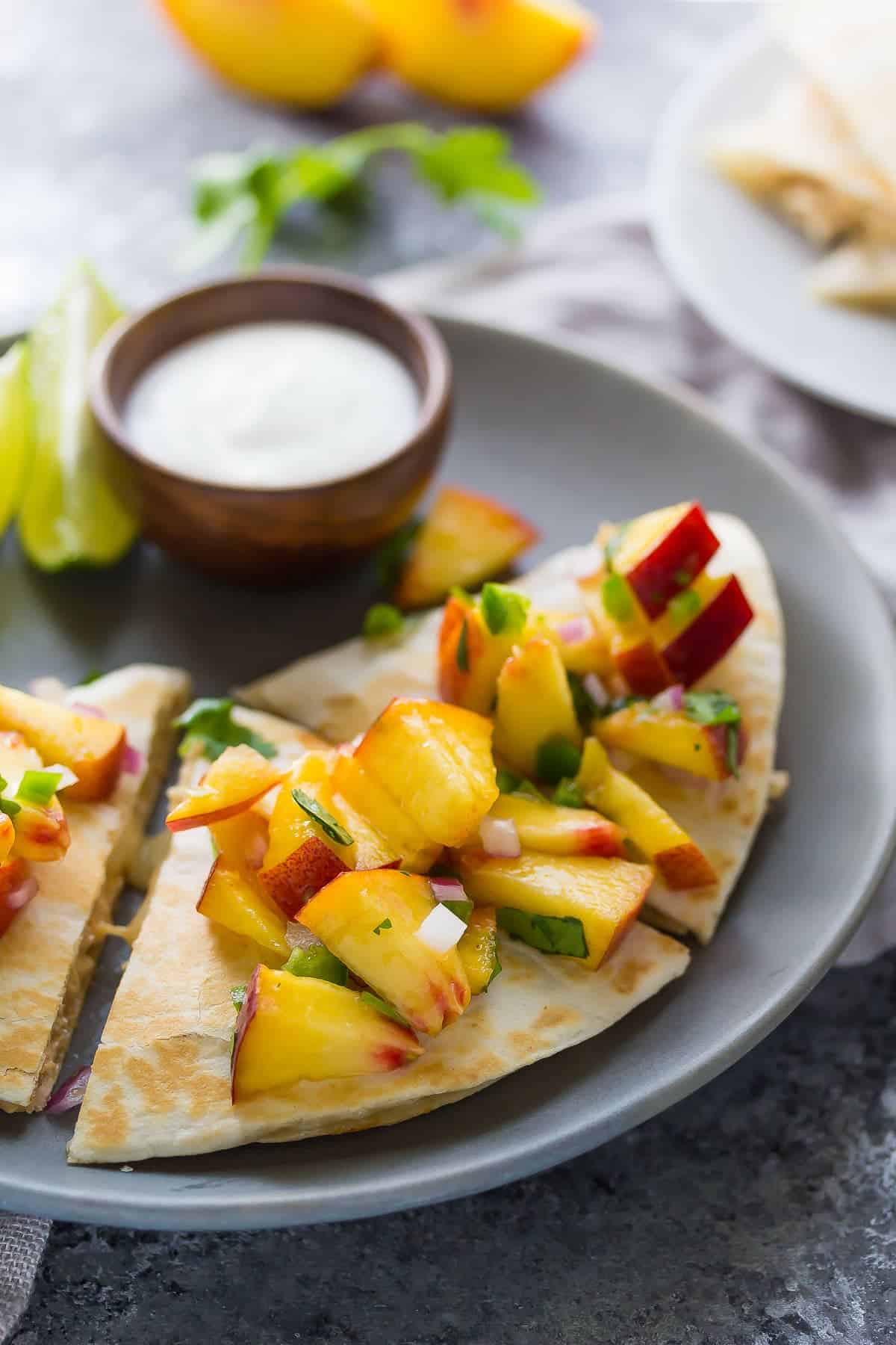 Sweet Chili Chicken Quesadillas with Peach Salsa on a plate with sour cream for dipping