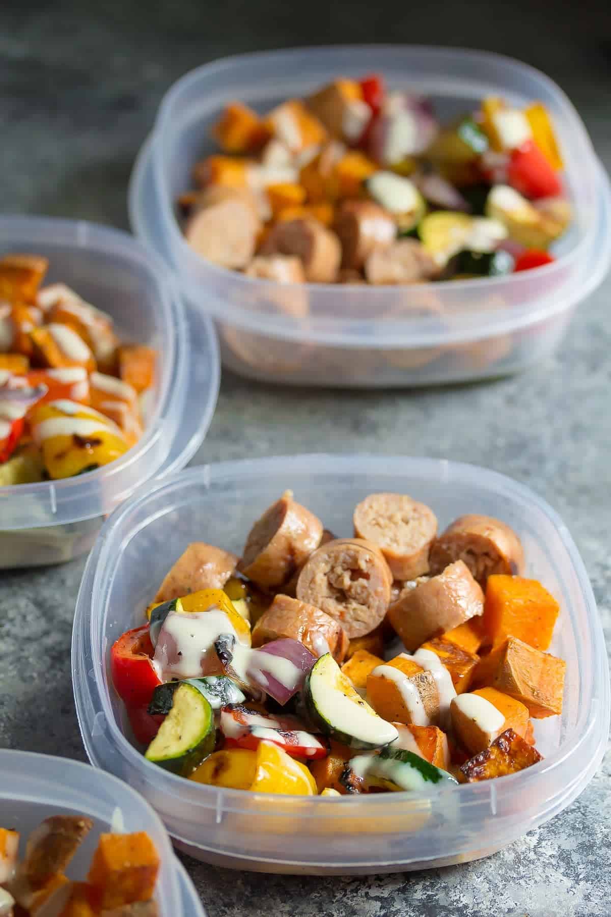 side angle view of three portions of Turkey Sausage & Sweet Potato Lunch Bowls in meal prep containers