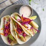 three sweet chili chicken tacos on gray plate with dipping sauce