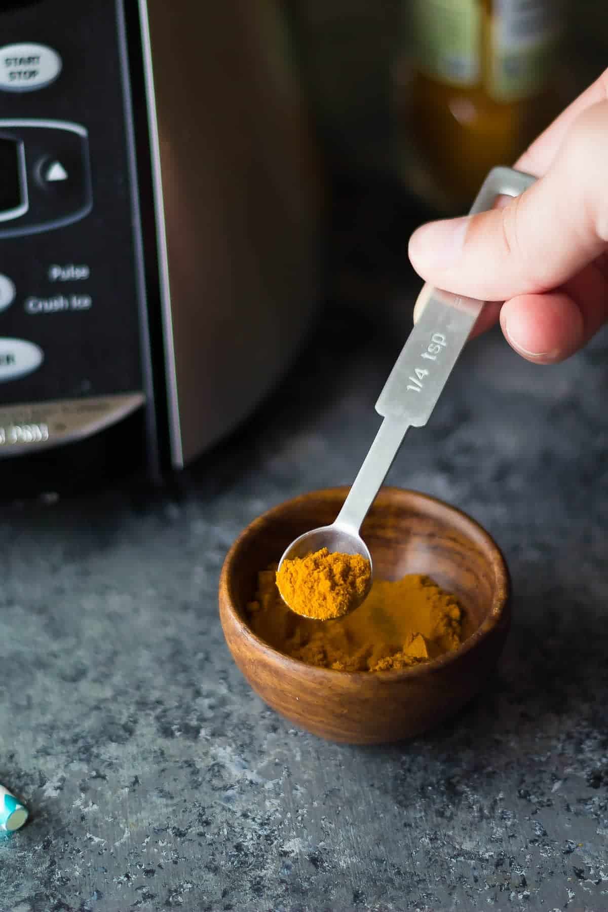 scooping turmeric on measuring spoon
