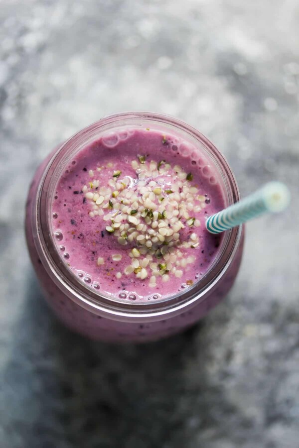 blueberry coconut water smoothie with blue straw in mason jar