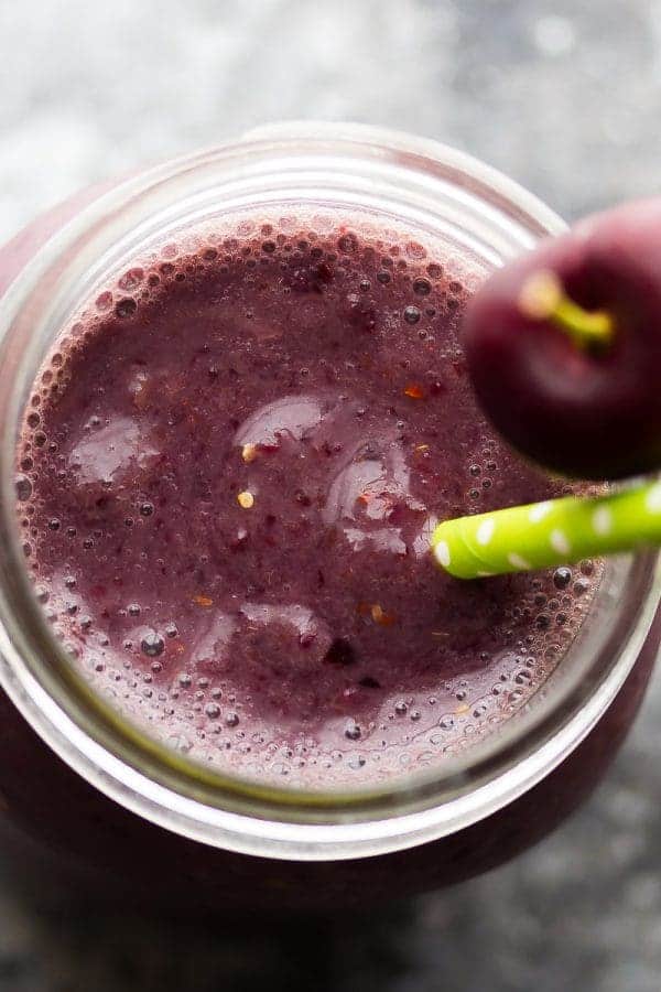 overhead shot of cherry peach goji berry smoothie in mason jar with cherry and straw