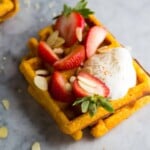 two sweet potato waffles with cream, almonds and strawberries