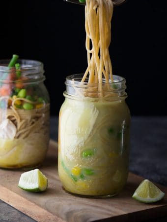 two mason jars with thai coconut instant noodles and lime wedges
