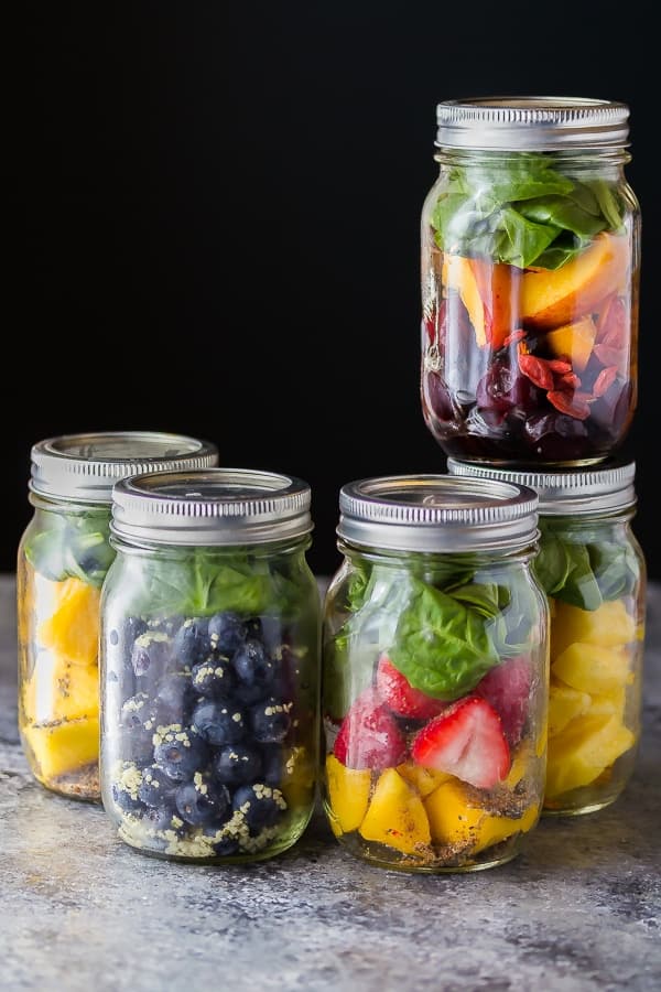 five glass jars filled with smoothie ingredients