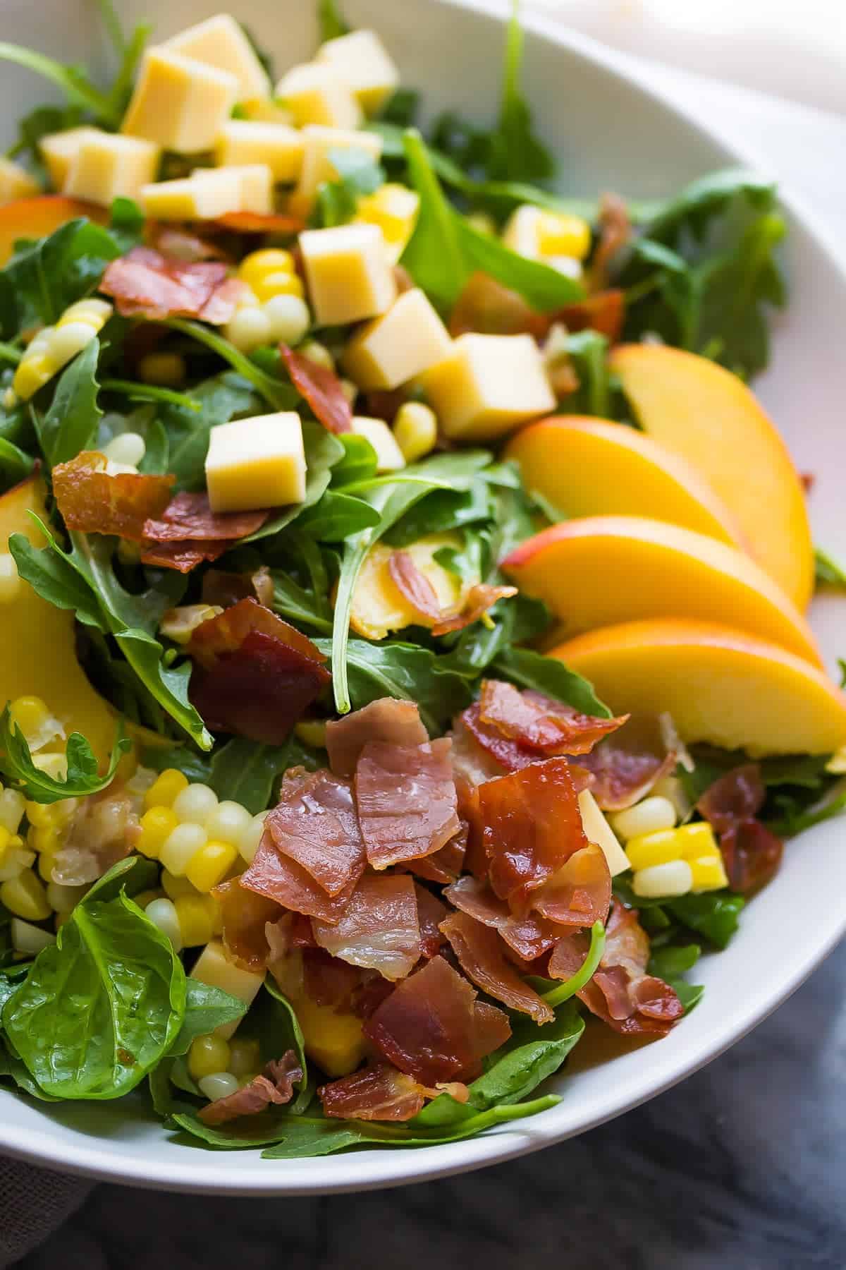 close up shot of peach corn salad in white bowl