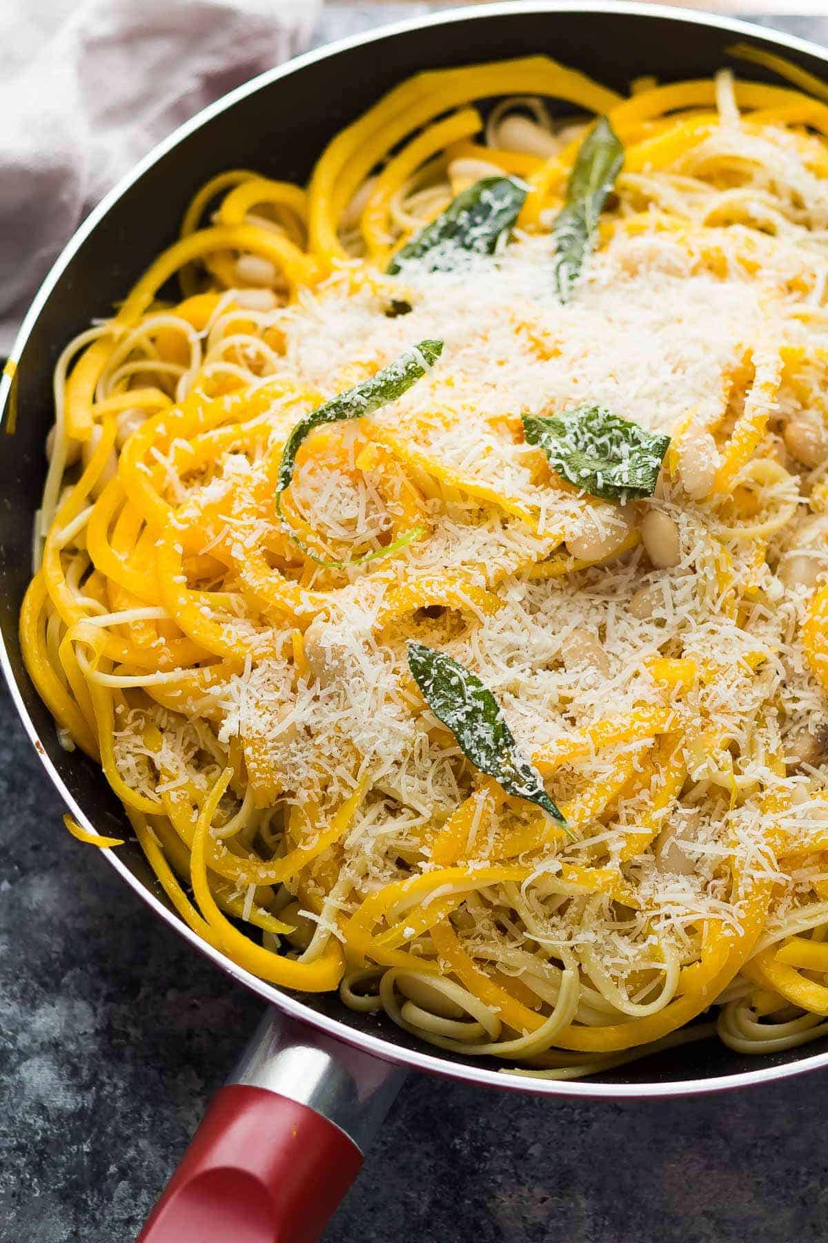 butternut squash noodles with sage, white beans and linguine in pan covered with parmesan cheese