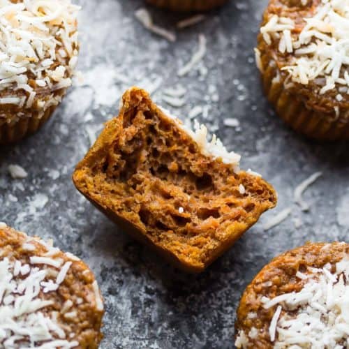 Carrot lentil protein muffins with a bite taken out of one on gray background