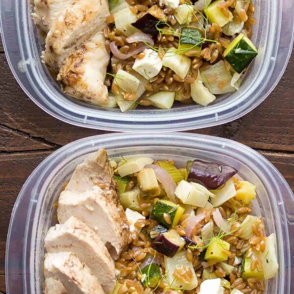 overhead shot of two plastic containers filled with mediterranean farro chicken lunch bowls