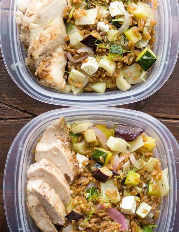 overhead shot of two plastic containers filled with mediterranean farro chicken lunch bowls
