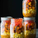 four mason jars filled with southwestern lentil sweet potato lunch bowls