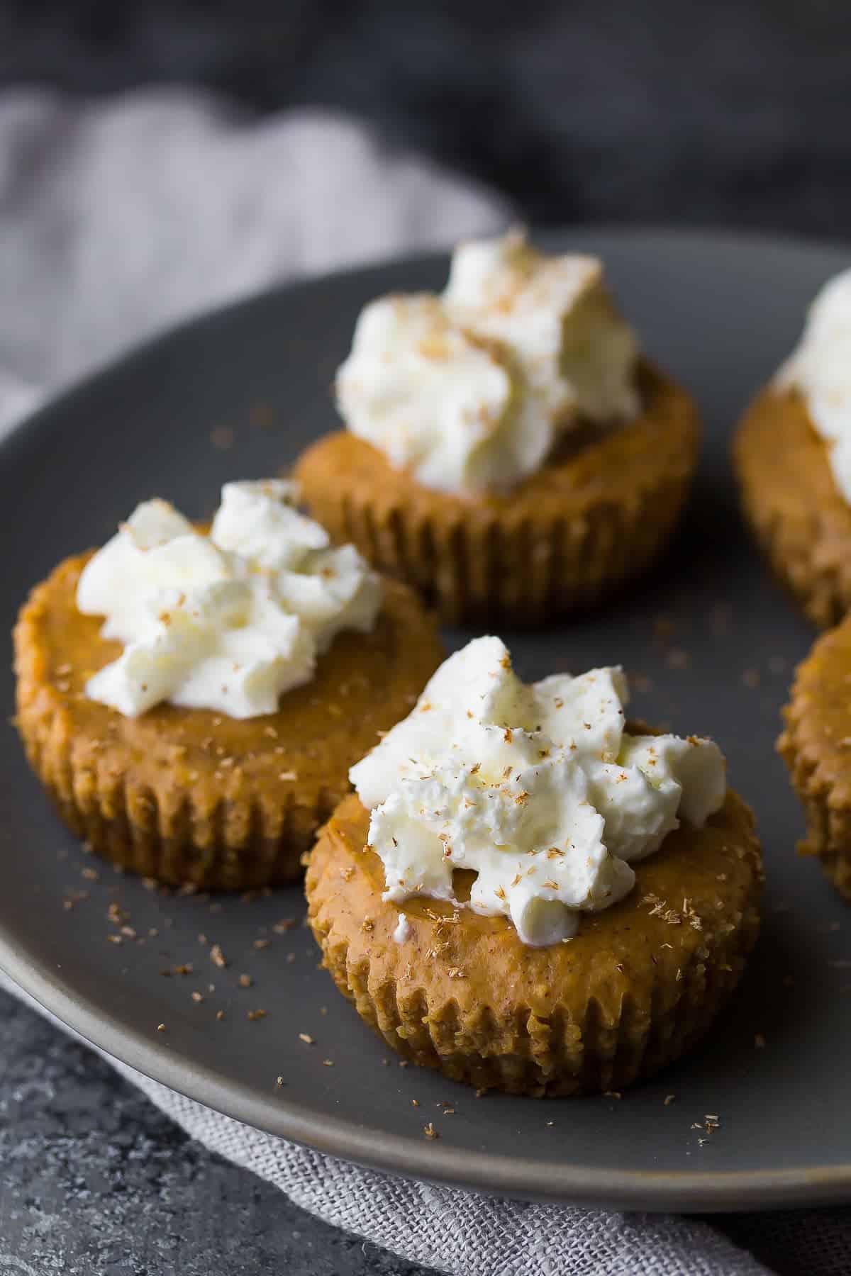 mini pumpkin greek yogurt cheesecakes on plate with whipped cream on top