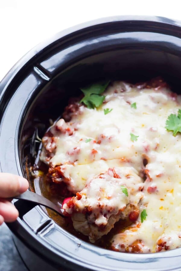 hand scooping spoonful of mexican chicken thighs out of the slow cooker