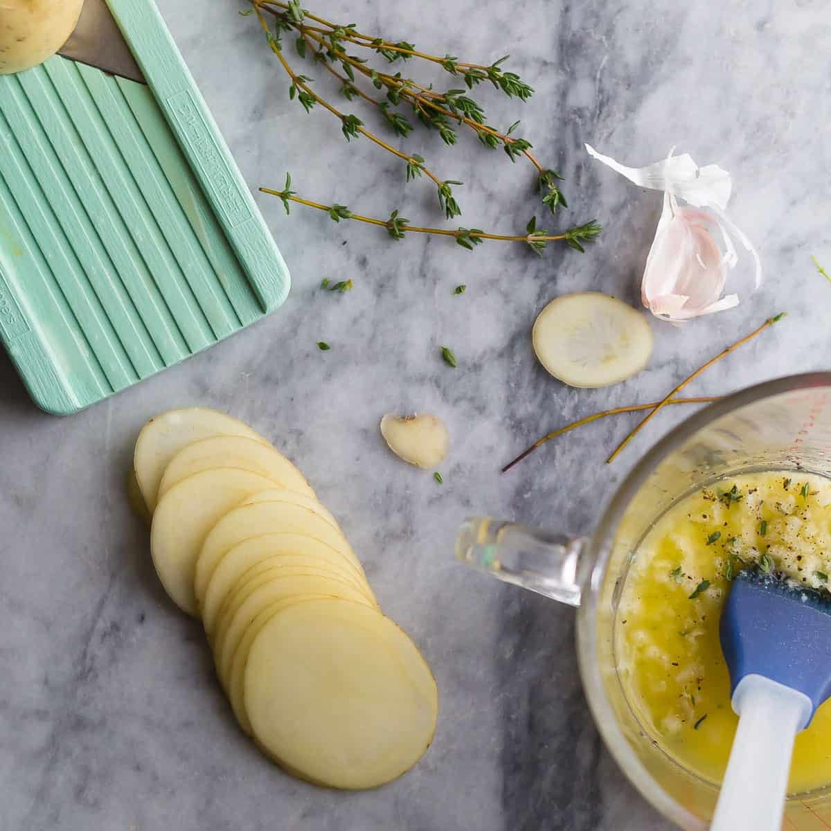 overhead view of sliced potatoes with herbs and butter