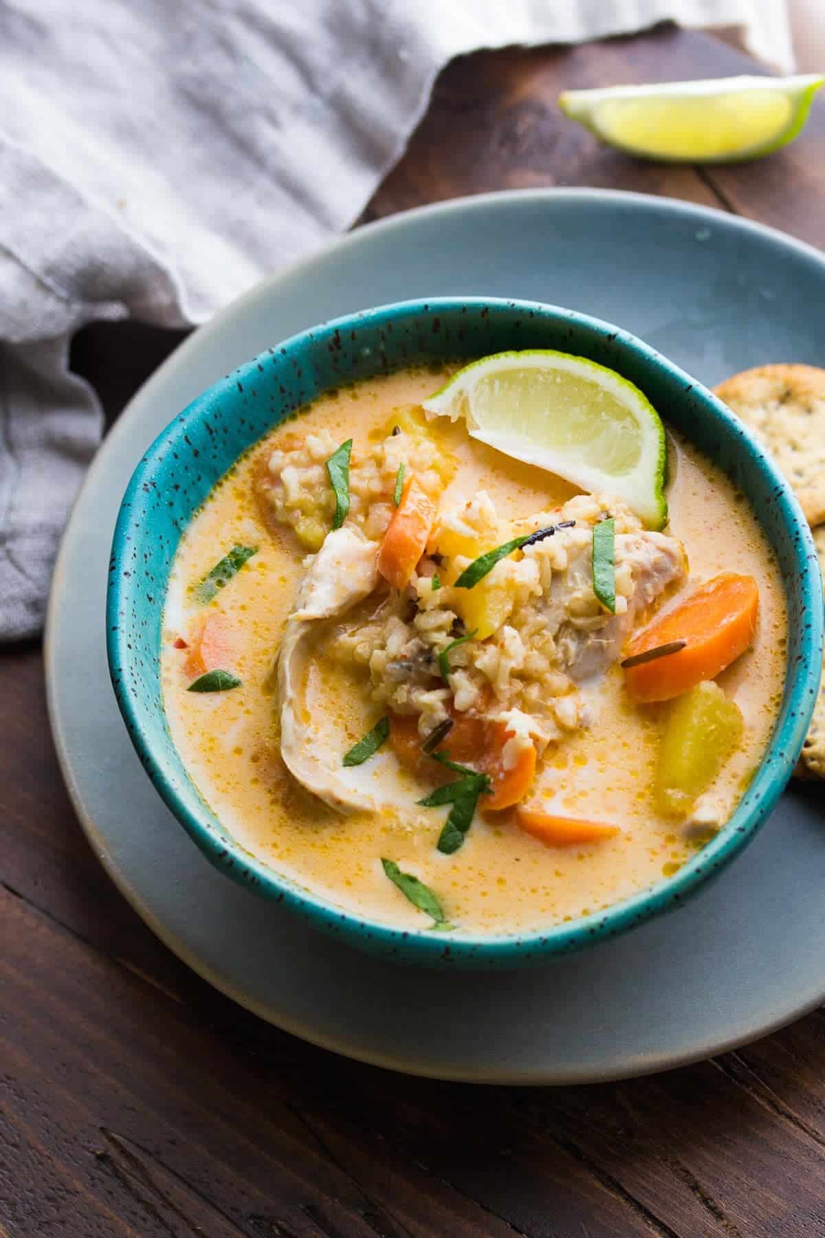 thai slow cooker chicken and wild rice soup in a bowl with lime wedges