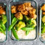 overhead shot of glass meal prep containers filled with honey sesame chicken lunch bowls