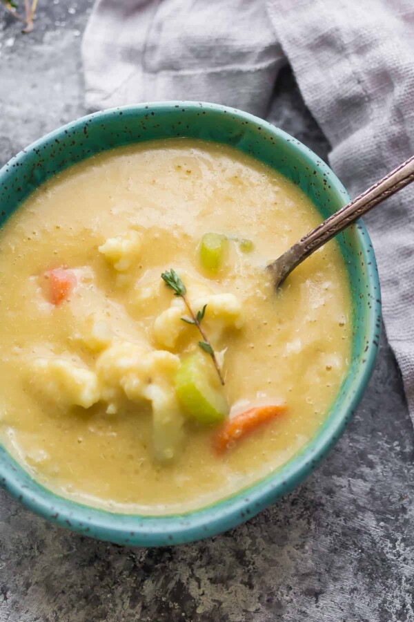 blue bowl filled with quinoa and cauliflower chowder with spoon