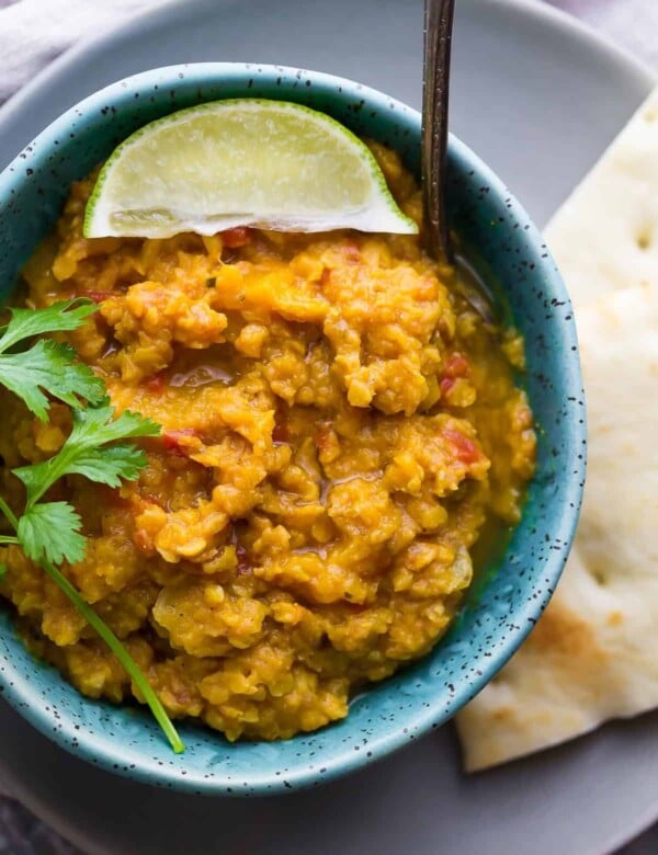 close up shot of blue bowl filled with butternut squash lentil curry and fresh lime wedge