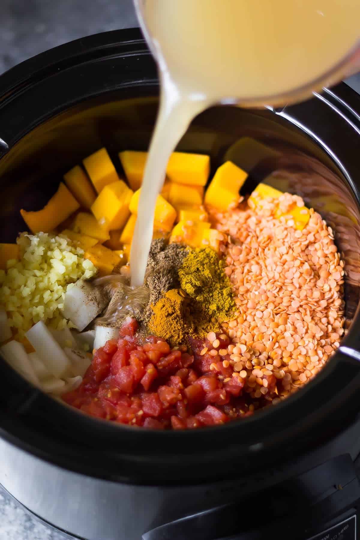 pouring the stock into the slow cooker to make butternut squash curry