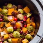 slow cooker filled with brussels sprouts cranberries butternut squash and pecans