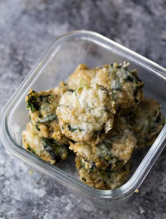 glass meal prep container with cheesy spinach quinoa cups on gray counter